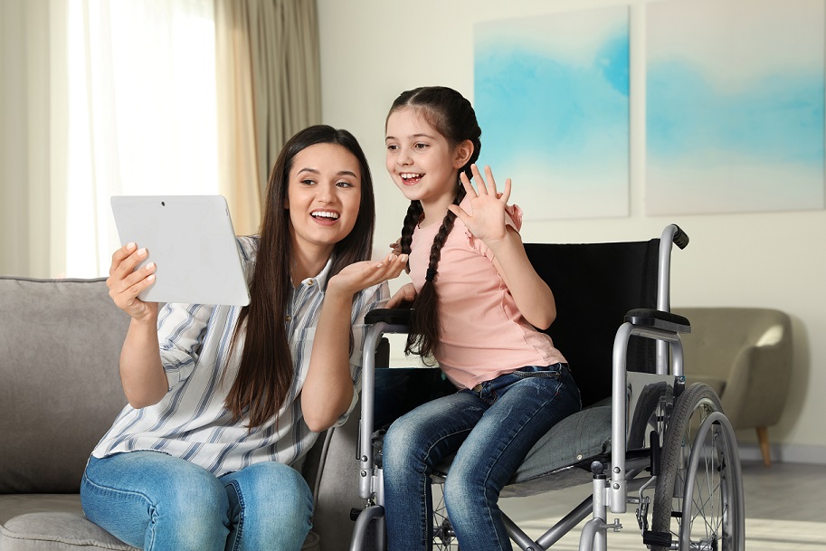 girl-in-wheelchair-and-her-mother-using-video-chat-on-tablet-at-home